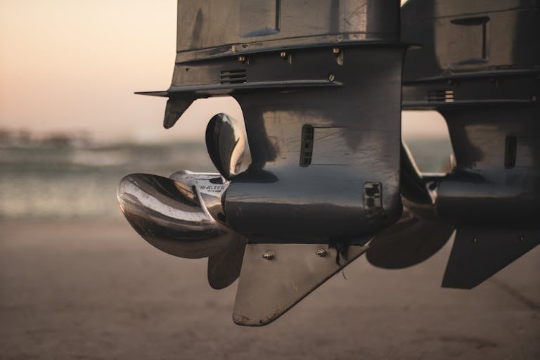 Detailed close-up of stainless steel boat propellers at sunset by the waterside.